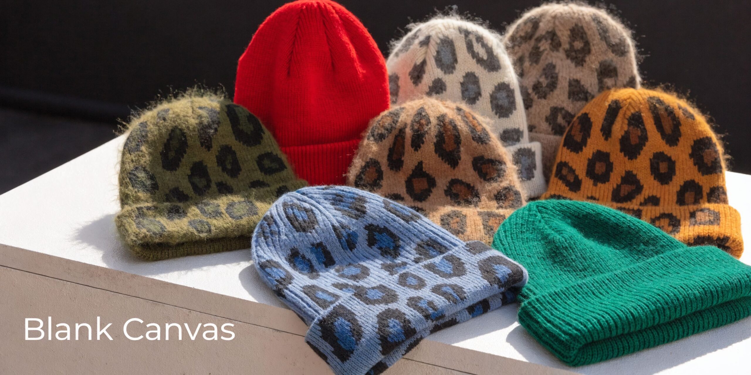 A collection of colorful knit beanies with leopard print patterns and solid red and green designs.