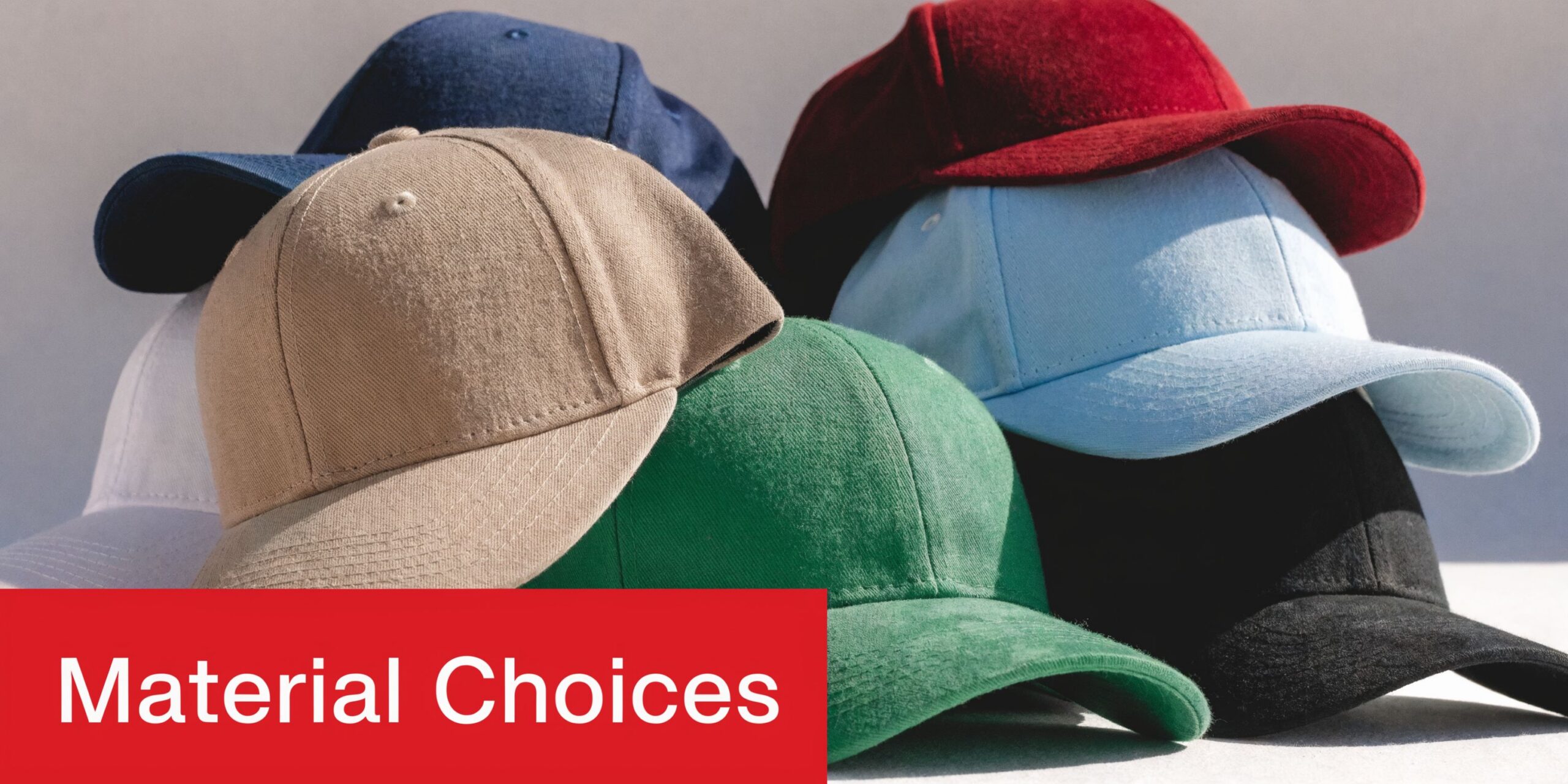 A stack of various colored blank baseball caps arranged together with a bold red banner underneath.