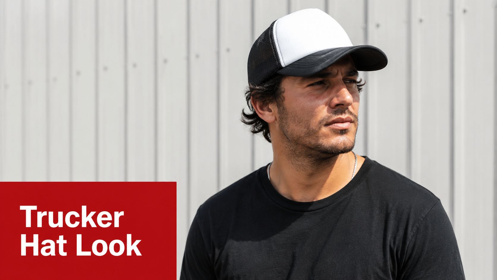 A man wearing a black and white trucker hat while standing in front of a metal wall.