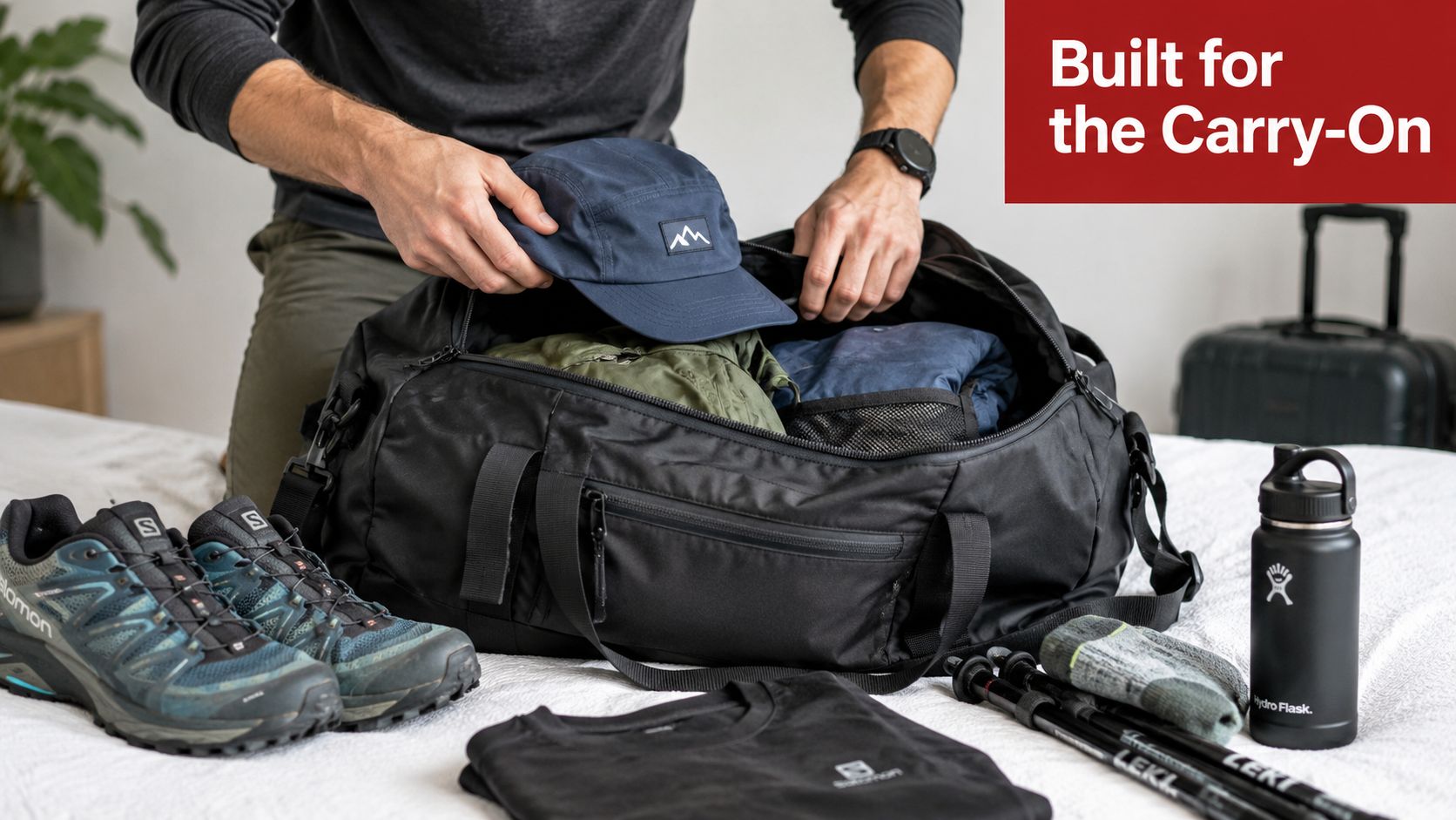 A person packing a black nylon 5 panel hat into a large black travel duffel bag.