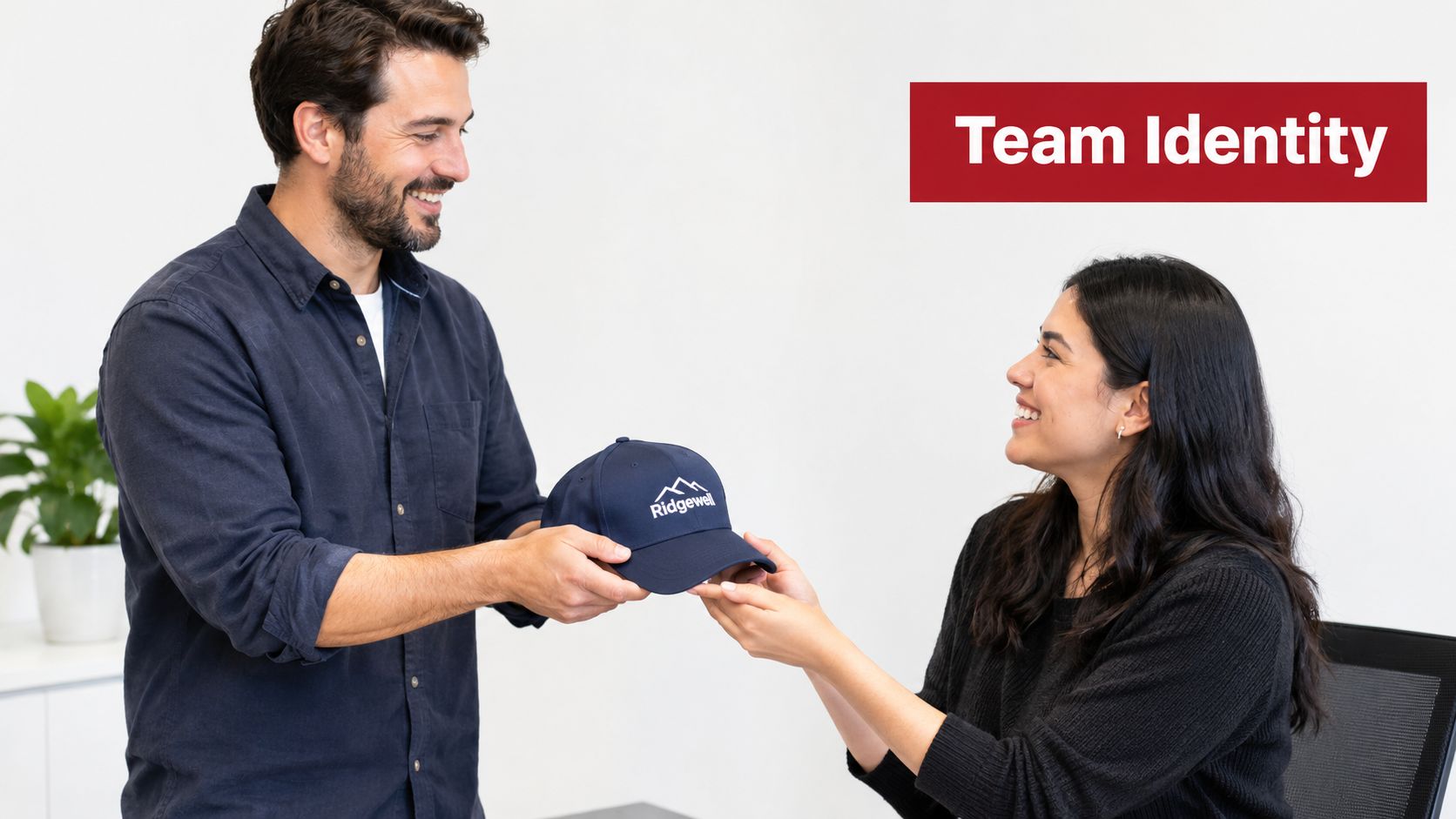 A man handing a navy blue baseball cap with a mountain logo to a smiling woman.